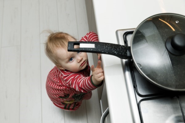 Toddler reaching for pan handle on stovetop