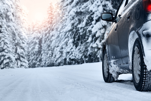 Image of car with winter tires driving on snow-packed rural road
