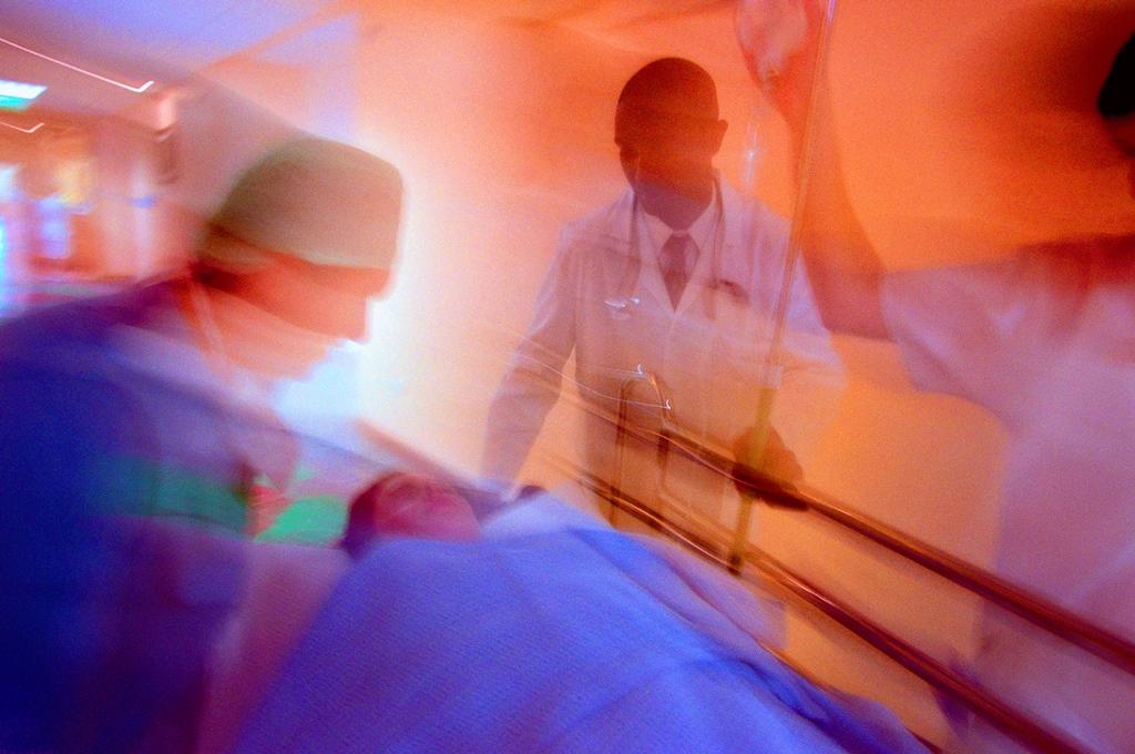 Photo of a trauma patient being transported in an urgent care clinical setting surrounded by doctors and clinicians.