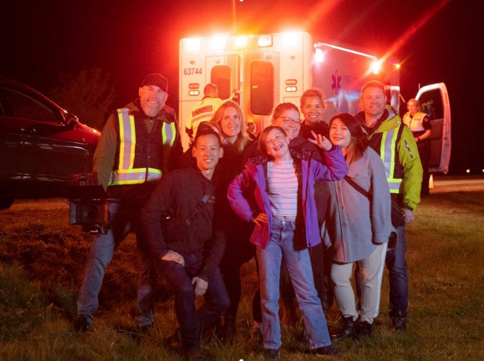 Group of people standing in front of ambulance at night