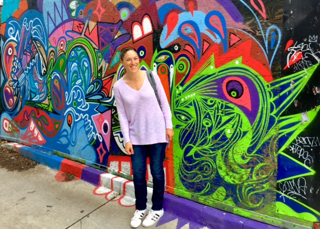 Woman standing in front of bright mural
