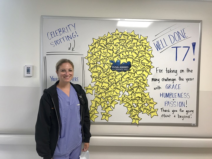 Woman in scrubs next to whiteboard covered in stars and congratulations