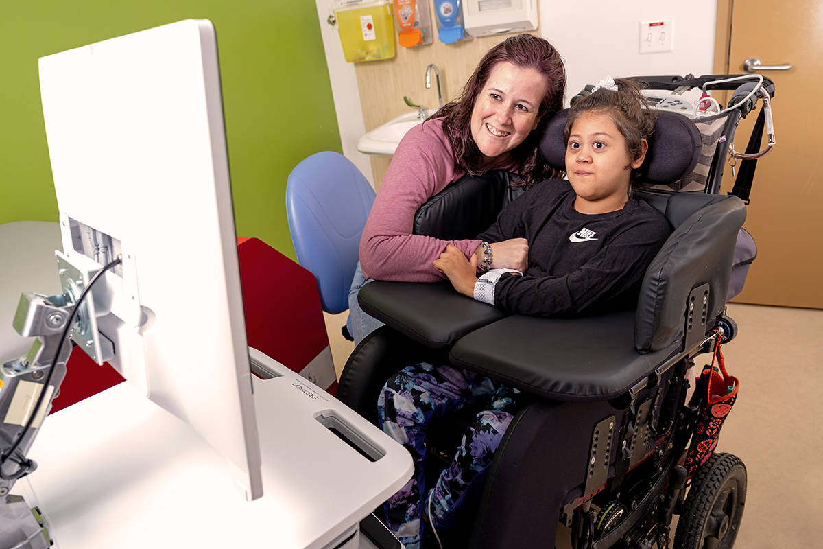 Child in wheelchair and carer looking at computer monitor