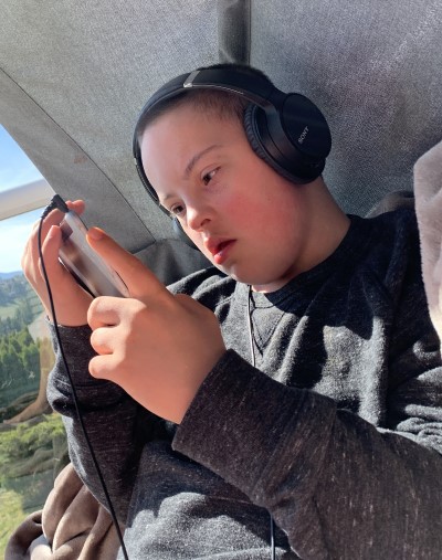 Child with Down's syndrome wearing headphones and looking at cellphone