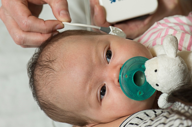 Baby with an instrument being held against their ear