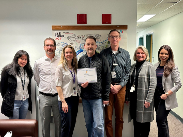 Seven people pose with an award certificate